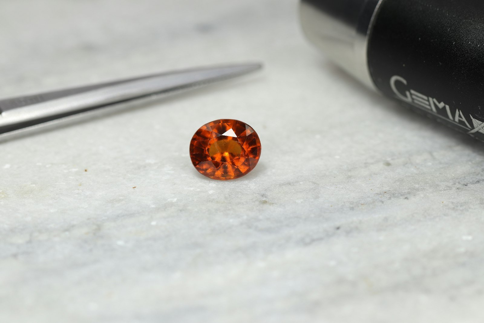 A loose garnet gemstone being examined with a jeweller's tool